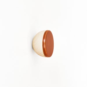 May include: A wooden knob with a brown leather top. The knob is round and has a smooth surface.