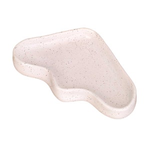 May include: A light pink ceramic serving tray with a speckled finish and an irregular, wavy shape.
