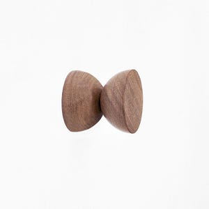 May include: A wooden wall hook with a unique hourglass shape. The hook is made of dark brown wood and has a smooth, polished finish.