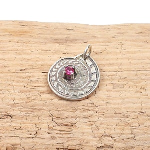 May include: A silver pendant with a pink gemstone set in a spiral design.