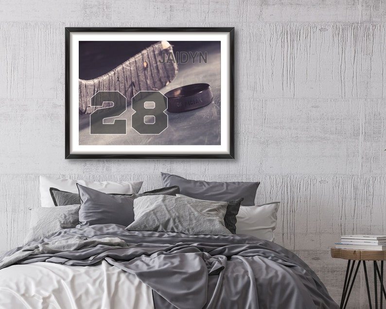 May include: A framed print of a hockey stick with the number 28 and the name Jaidyn. A ring with the words "Of Kings" is resting on the stick.