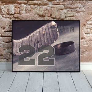 May include: A black and white photo of a hockey stick and puck with the number 22 and the name Austin printed on it.