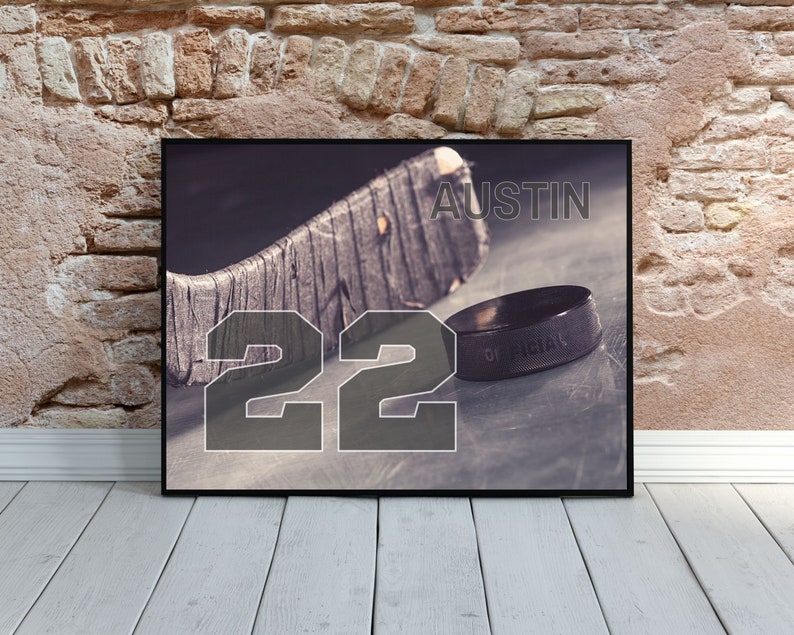 May include: A black and white photo of a hockey stick and puck with the number 22 and the name Austin printed on it.