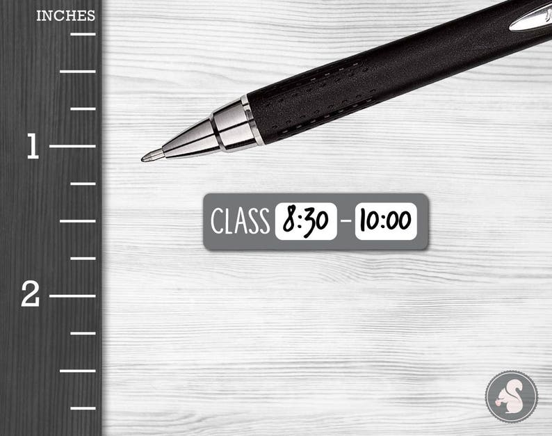 May include: A gray sticker with the text "CLASS 8:30 - 10:00" on a white wooden surface. A black pen is lying on the surface.