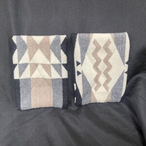 May include: Two fabric swatches with geometric patterns. One swatch has a black, white, and brown geometric pattern with triangles. The other swatch has a black, white, and brown geometric pattern with wavy lines.