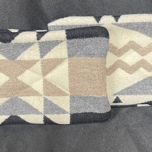 May include: Two decorative throw pillows with geometric patterns in shades of gray, brown, and white. The pillows are made of a soft, woven fabric.