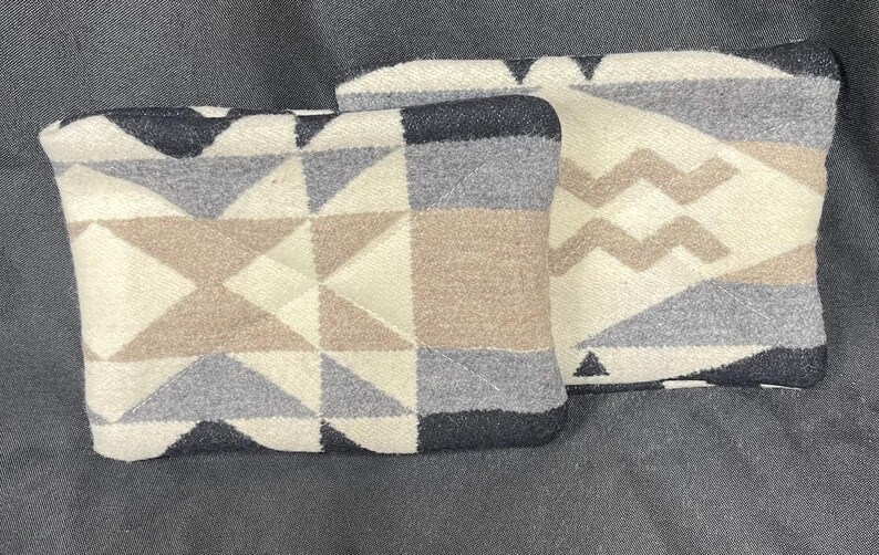 May include: Two decorative throw pillows with geometric patterns in shades of gray, brown, and white. The pillows are made of a soft, woven fabric.