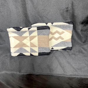 May include: Two decorative pillows with geometric patterns in shades of black, white, gray, and brown. The pillows are made of a soft, woven fabric.