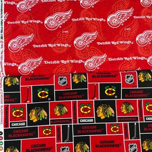 May include: Red and black fabric with a repeating pattern of the Detroit Red Wings and Chicago Blackhawks logos. The Detroit Red Wings logo features a red wing with a white outline and the text "Detroit Red Wings" in white. The Chicago Blackhawks logo features a black Indian head with a red feather headdress and the text "Chicago Blackhawks" in white.