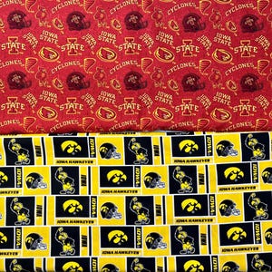 May include: Two fabric swatches, one red with a white and yellow pattern of the Iowa State Cyclones logo and the other yellow with a black and white pattern of the Iowa Hawkeyes logo.