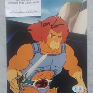 May include: A vintage cartoon print featuring a muscular character with orange skin, red hair, and a blue outfit, holding a sword. The print includes the text "DO NOT COPY ORIGINAL ITEM ORIGINAL ETSY LISTING FROM Canadian Graphiti".