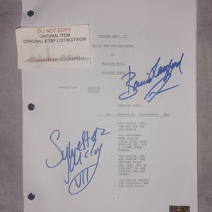Pode incluir: Uma página de roteiro assinada de "Doctor Who: Delta and the Bannermen" com texto e assinaturas. A página inclui o título do episódio, o escritor e o número do episódio. Um adesivo de "Canadian Graphiti" é visível.