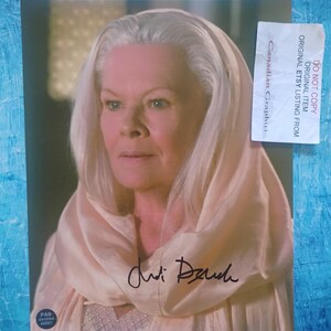 Peut inclure: Portrait d'une femme aux cheveux blancs et portant un châle de couleur claire. L'image comprend un autographe et un autocollant indiquant "Canadian Graphiti". La femme regarde légèrement vers la gauche.