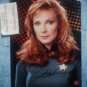 May include: A portrait of a woman with auburn hair, wearing a teal uniform with a Starfleet insignia pin. The image includes an autograph and a sticker that reads "DO NOT COPY ORIGINAL ITEM ORIGINAL ETSY LISTING FROM Canadian Graphici".