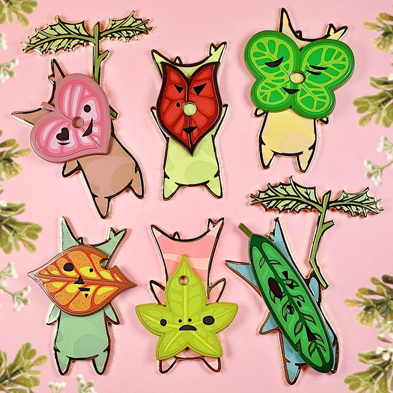 May include: Set of 8 enamel pins featuring different characters from the video game "The Legend of Zelda: Majora's Mask". The pins are colorful and feature a variety of designs, including a heart, a leaf, and a mask.