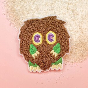 May include: Brown fuzzy owl applique with green leaves and yellow and purple embroidered eyes.