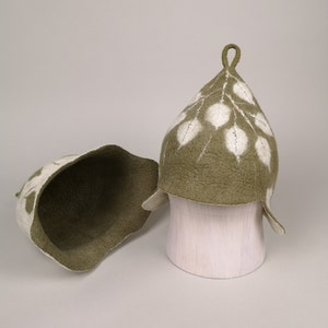 May include: Two green felt hats with white leaf designs. One hat is turned inside out to show the interior.