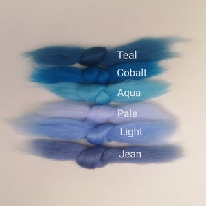 May include: Six skeins of wool yarn in shades of blue, from teal to jean. The skeins are arranged in a gradient from darkest to lightest, with the labels "Teal", "Cobalt", "Aqua", "Pale", "Light", and "Jean" visible.