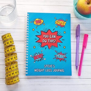 Weight Loss Journal ~  Diet Diary. Slimming World Compatible. A5 Size wire bound notebook. Title: You can do this! Personalised with your name. Blue background, red 10 point star and comic style words- yes, super,wow and yeah on the cover.