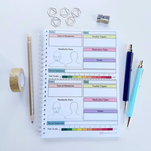 May include: A spiral bound notebook with a pink, yellow, and blue cover. The notebook has a section for tracking headaches, including the type of headache, possible triggers, medication taken, and notes. There is also a section for tracking period symptoms, including a pain scale.