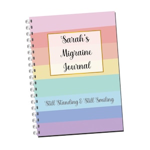 May include: A colorful spiral bound journal with the text "Sarah's Migraine Journal" in a gold frame and the text "Still Standing & Still Smiling" at the bottom.