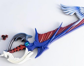 May include: A blue and red plastic keyblade with a white wing on one side and a black wing on the other. The keyblade has a chain with a red heart charm attached.