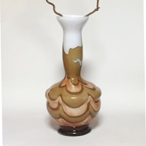 May include: A tall, brown and white ceramic vase with a swirling pattern. The vase has a wide base and a narrow neck.