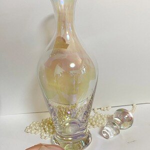May include: A clear iridescent glass bottle with a wide base and a narrow neck. The bottle has a pearlescent finish and is perfect for displaying flowers or other decorative items.