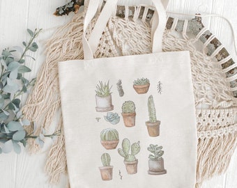 May include: A white canvas tote bag with a design of various potted cacti and succulents. The bag has brown straps and a natural fabric texture.