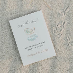 Könnte beinhalten: Eine rechteckige, weiße Save the Date-Karte mit einer Aquarellillustration von zwei Austernschalen. Der Text lautet Save the Date, FOR THE WEDDING OF ELLIOT & STELLA und August 8, 2026, gedruckt in schwarzen und grauen Serif- und Schreibschriften.