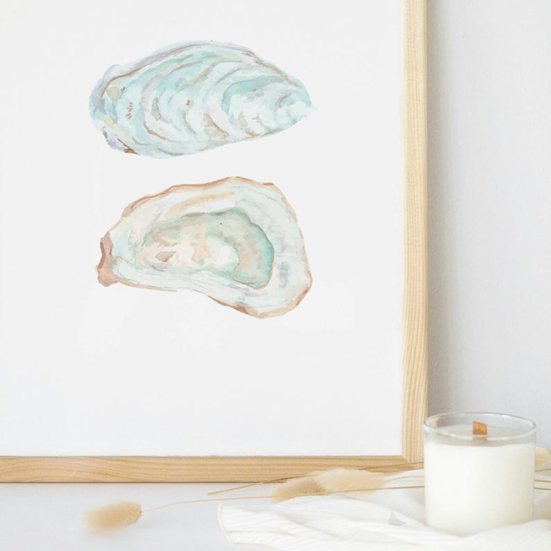 Puede incluir: Una pintura de acuarela de dos conchas de ostra. Las conchas est&aacute;n pintadas en tonos de azul, verde y marr&oacute;n. La pintura est&aacute; enmarcada en un marco de madera claro.