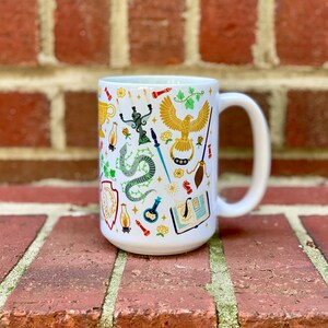 May include: White ceramic mug with a colorful pattern of magical objects, including a snake, a phoenix, a wand, a book, a cauldron, and a broom.