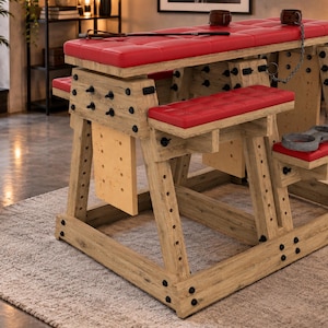 May include: A wooden furniture piece with a light brown finish, featuring multiple red tufted cushions, black metal hardware, and integrated metal chains with cuffs. The structure includes adjustable support beams and various attachment points.