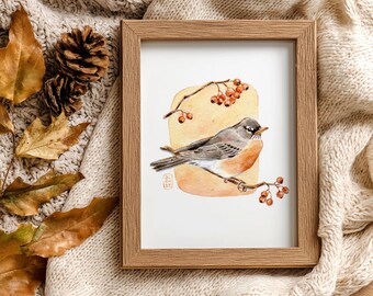 May include: A framed watercolor print of a bird perched on a branch with berries. The artwork features a neutral color palette with shades of brown, gray, and orange. The frame is made of light brown wood, and the print is set against a cream-colored background.