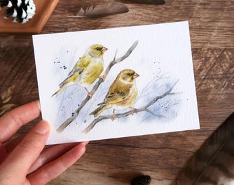May include: Watercolor painting of two small birds perched on a branch. The birds have yellow and brown feathers, with a light blue background and dark blue accents. The artwork is on white paper.