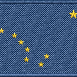 May include: Embroidered patch featuring the flag of Alaska. The design includes a dark blue background with a constellation of eight gold stars, and a gold star in the upper right corner. The patch has a blue border.