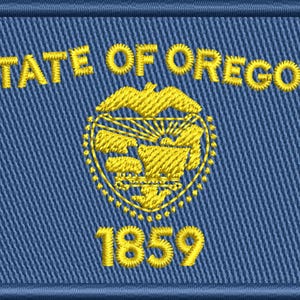 May include: Embroidered patch featuring the Oregon state flag design. The patch is rectangular with a blue background and a gold border. The words "STATE OF OREGON" and the year "1859" are embroidered in gold.