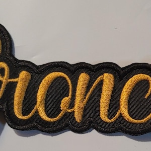 May include: Black embroidered patch with the word "Broncos" in gold lettering.