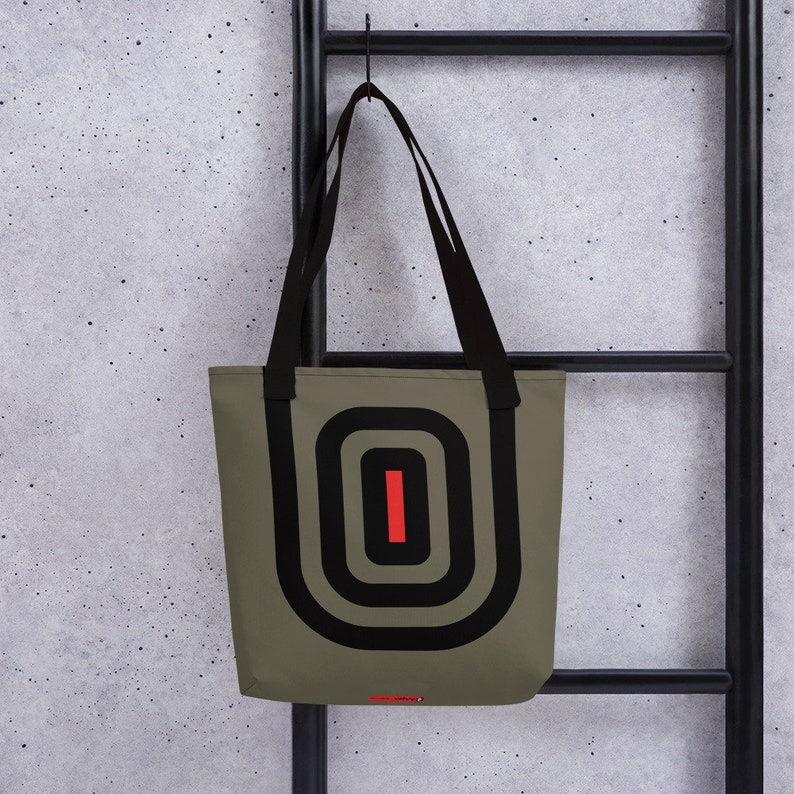 May include: A green tote bag with black and red geometric design. The bag has black straps and a large oval shape with concentric circles and a red line in the center.