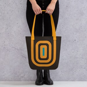 May include: A black tote bag with yellow and blue geometric design. The bag has two yellow straps.