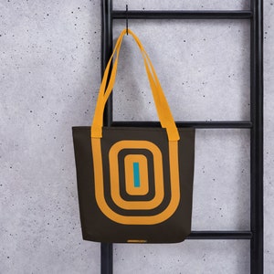 May include: A brown tote bag with yellow and blue geometric designs. The bag has two yellow straps.