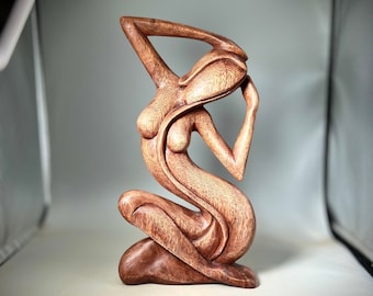 Könnte beinhalten: Eine Holzskulptur einer Frau in sitzender Pose mit erhobenen Armen über dem Kopf. Die Skulptur ist aus dunkelbraunem Holz gefertigt und hat eine glatte, polierte Oberfläche.