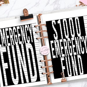 May include: A printable planner page with black and white text that reads "Emergency Fund" and "$1000 Emergency Fund". The text is on a white background with black lines.