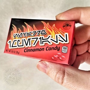 May include: A red box of "10CM71KN" cinnamon candy, with flames graphic and the text "AVYK770". The box contains 0.9 oz (28g) of candy and 100 calories per package.