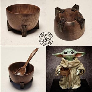 Puede incluir: Un conjunto de cuencos de madera hechos a mano con un acabado marr&oacute;n oscuro. Cada cuenco est&aacute; soportado por tres peque&ntilde;as patas rectangulares. Un cuenco contiene una cuchara de madera. La imagen tambi&eacute;n presenta una figura de Grogu.