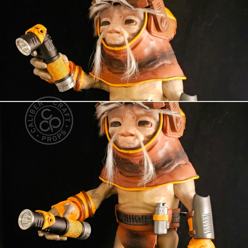 May include: A detailed figurine of a creature with light skin, long white facial hair, and a brown hood. The figure wears orange and brown arm guards, a utility belt with a silver canister, and holds a black and yellow flashlight in its hand.