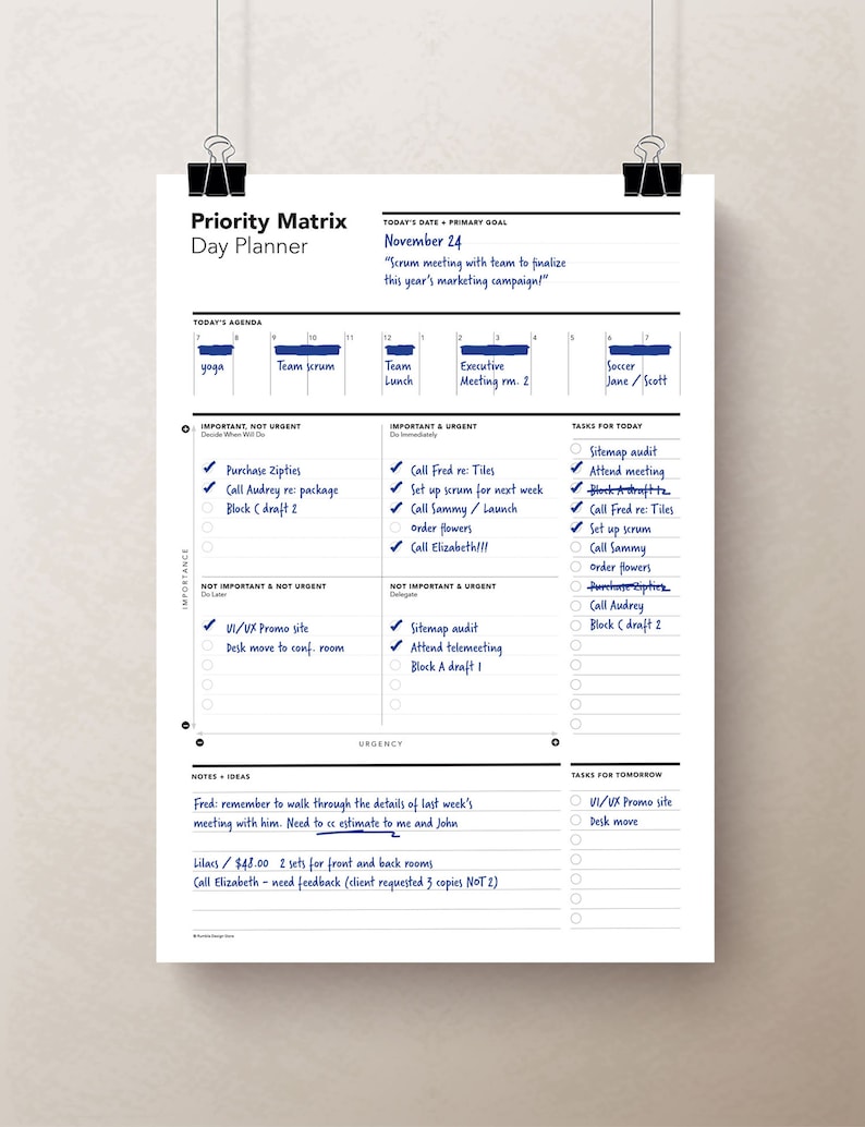 Peut inclure: Un agenda quotidien bleu et blanc avec une matrice de priorit&eacute; pour organiser les t&acirc;ches. L'agenda est dat&eacute; du 24 novembre et comprend une liste de t&acirc;ches pour la journ&eacute;e, notamment "Appeler Fred pour les tuiles", "Mettre en place un scrum pour la semaine prochaine", "Appeler Sammy/Lancer la commande de fleurs", et "Appeler Elizabeth!!!". L'agenda comprend &eacute;galement une liste de t&acirc;ches pour le lendemain, notamment "Site Web UI/UX Promo" et "D&eacute;placer le bureau".