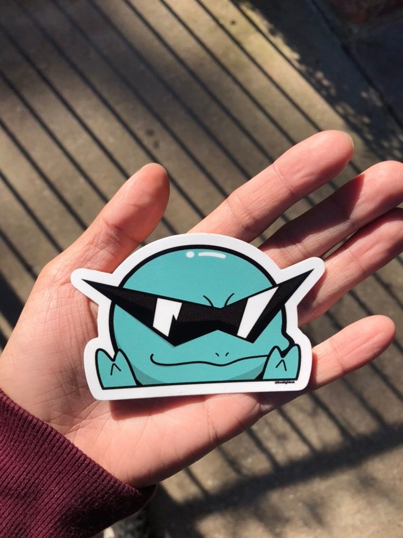 May include: A teal green cartoon character with sunglasses and a smirk. The character is wearing a white outline and is on a white background.
