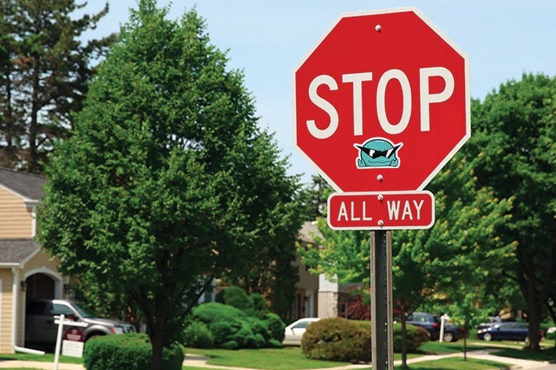 May include: A red stop sign with white lettering that reads "STOP" and "ALL WAY". A blue cartoon character with sunglasses is on the sign.