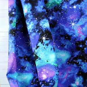 Può includere: Tessuto blu con stampa galattica con stelle bianche e nebulose in tonalità di blu, viola e verde.